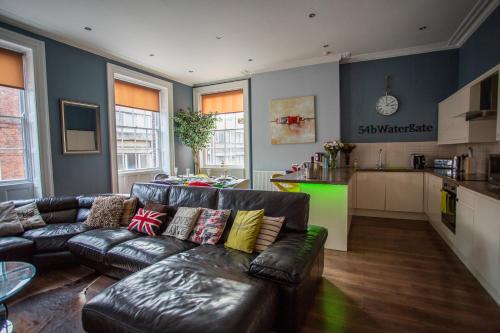 a living room with a leather couch and a kitchen at Most central luxury apartment - sleeps 4 & FREE parking! in Chester