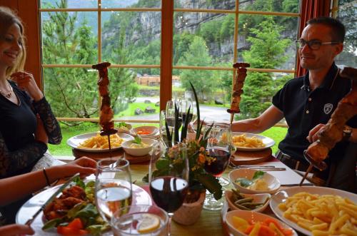 a group of people sitting at a table with food at Hüttenhotel Husky Lodge in Muotathal