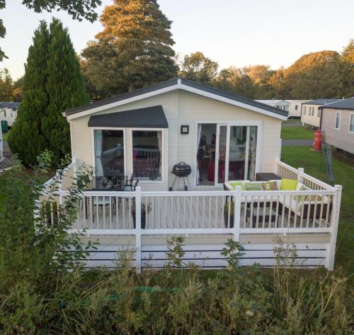a tiny house with a porch and a deck at Haggerston Lola the Lodge and Betty the Van in Cheswick