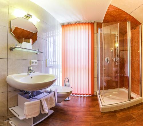 uma casa de banho com um lavatório, um chuveiro e um WC. em Kneipp-Kurhotel Emilie em Bad Wörishofen