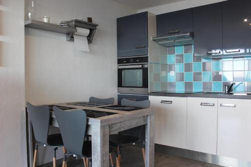 a kitchen with a table and some chairs in it at Nicolas Lambert - Appartement vue mer, prêt de velos,WIFI in Quiberon