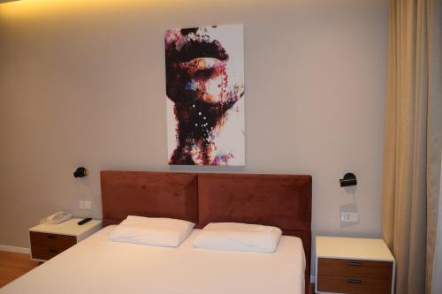 a bedroom with a bed with a painting on the wall at Star Hotel in Tirana