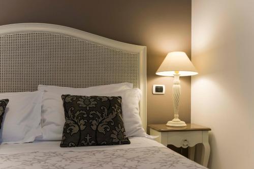 a bed with a black and white pillow and a lamp at Tenuta D'Amore in San Mango Piemonte