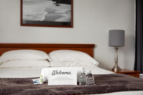 a bed with a welcome sign and two bottles of water at Travel Inn of Titusville in Titusville