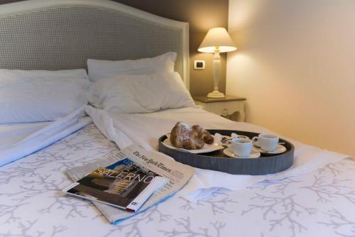 a tray with a muffin and cups and a book on a bed at Tenuta D'Amore in San Mango Piemonte