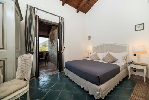 a bedroom with a bed and a chair and a window at Tenuta D'Amore in San Mango Piemonte