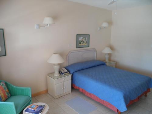 a bedroom with a blue bed and a chair at Hotel PomMarine in Bridgetown