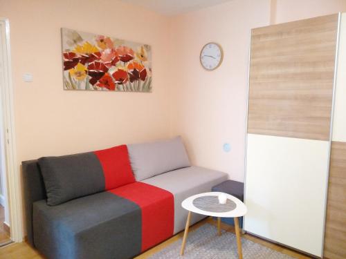 a living room with a couch and a clock on the wall at Sunray Studio Apartment in Zagreb