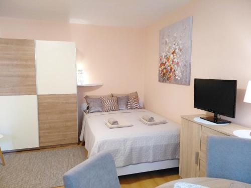 um pequeno quarto com uma cama e uma televisão em Sunray Studio Apartment em Zagreb