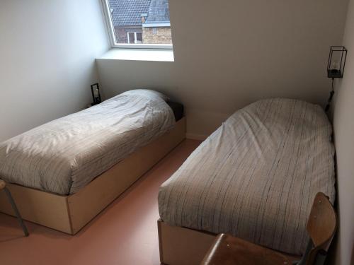 two beds in a small room with a window at Nelly in Ypres