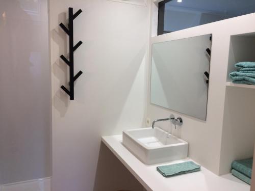 a white bathroom with a sink and a mirror at Nelly in Ypres