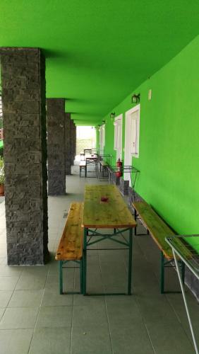 a green room with a wooden table and benches at Apartman Taktik in Veľký Meder