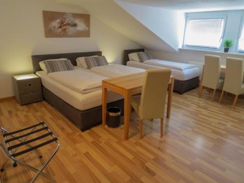 Habitación con 2 camas, mesa y sillas en Hotel Saarblick Mettlach, en Mettlach
