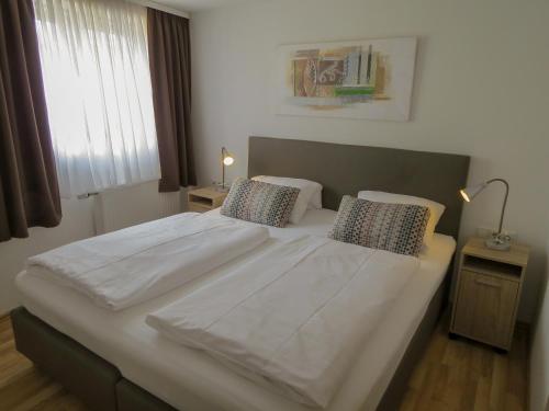 Hotel Saarblick Mettlach في ميتلاخ: غرفة نوم بسرير ابيض كبير مع وسادتين