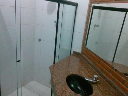 a bathroom with a sink and a shower with a mirror at Pousada Kantuta in Mucuri