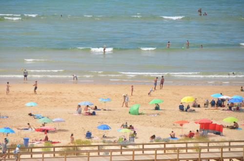 a group of people on a beach with umbrellas at Monte Gordo T1 Parque dos Reis in Monte Gordo