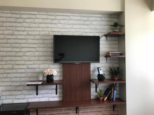 TV de pantalla plana en una pared de ladrillo en Joaquim Vacation Homes en Davao