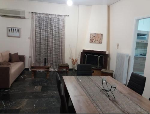 een woonkamer met een tafel en een bank bij Comfortable 4th fl flat ideal for up to 8 people in Pýrgos