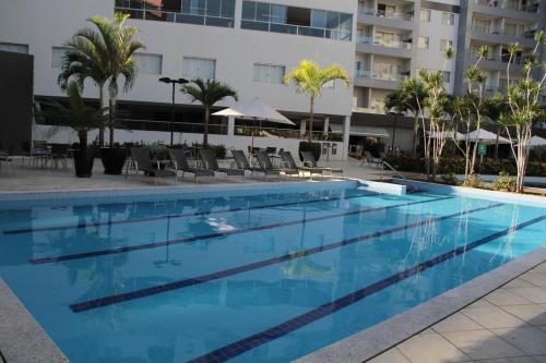 a large swimming pool with chairs and a building at Flat209 Veredas Rio Quente Particular in Rio Quente