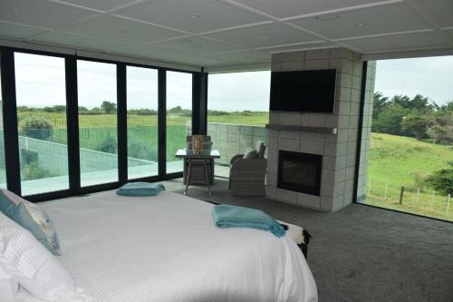 a bedroom with a bed with a fireplace and a television at 157 Field Way Luxury Lodge in Waikanae