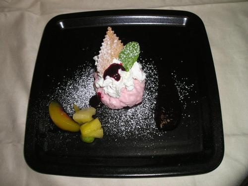a black plate with a dessert on a table at Logis Hôtel Restaurant La Tête Des Faux in Le Bonhomme
