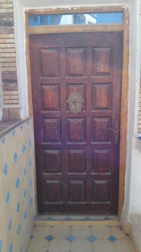a large wooden door in a room with a tile floor at tamazirt surf house in Taghazout