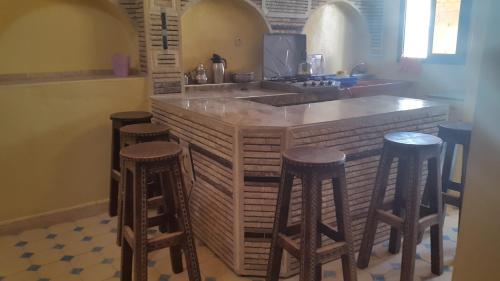 uma cozinha com um balcão com quatro bancos de bar em tamazirt surf house em Taghazout