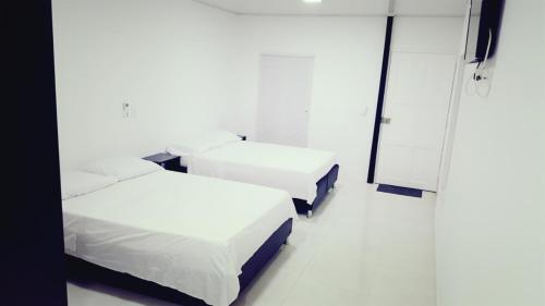 um quarto branco com 2 camas e um espelho em Apartamentos Hilal House em San Andrés