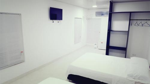 um quarto branco com uma cama e uma televisão em Apartamentos Hilal House em San Andrés