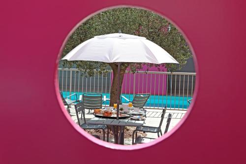 a table with a white umbrella and chairs at Logis Hotels Grand Hotel d'Orléans in Albi