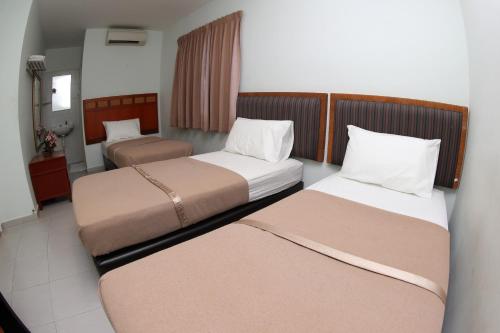 a hotel room with two beds and a chair at Hotel Rembia in Rembia