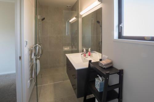 ein Bad mit einem Waschbecken und einer Dusche mit einem Spiegel in der Unterkunft Retreat for all seasons in Wanaka