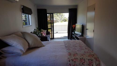 a bedroom with a bed with a television and a balcony at Long St Studio in Raglan