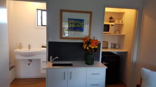 een keuken met een wastafel en een vaas met bloemen op een aanrecht bij Long St Studio in Raglan