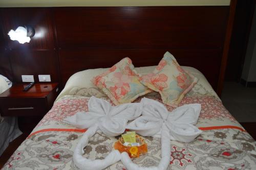 a bed with white towels on it with flowers on it at Balcones del Río Hotel in Latacunga