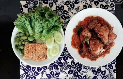 two plates of food and a salad on a table at Halumba Eco Villa Bali in Tejakula