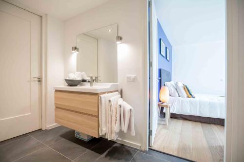 een badkamer met een wastafel, een spiegel en een bed bij Amsterdam Area Residence Oosterwold in Almere