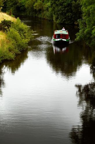 a boat is traveling down a river at Riversdale Farm B&B in Ballinamore