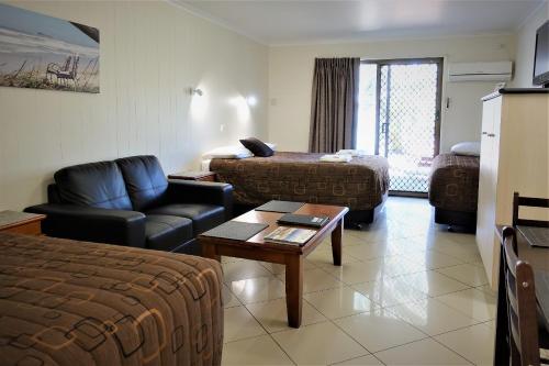 a hotel room with a living room with a bed and a couch at Pacific Palms Motor Inn in Marcoola