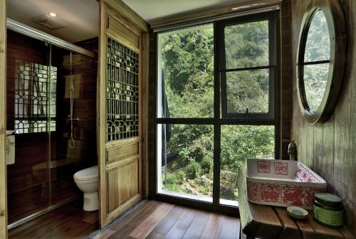 a bathroom with a toilet and a large window at Zhangjiajie One city one inn in Zhangjiajie