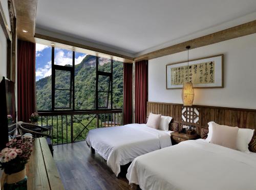 a hotel room with two beds and a large window at Zhangjiajie One city one inn in Zhangjiajie