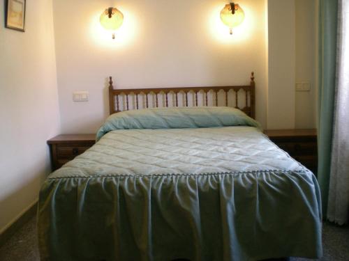 a bed in a bedroom with two lights on the wall at Hotel Puerta Romeros in Burgos