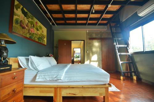 een slaapkamer met een groot bed en een ladder bij The Corner's unique house in Chiang Mai