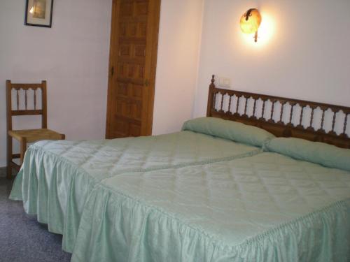 a bedroom with a large bed and a chair at Hotel Puerta Romeros in Burgos