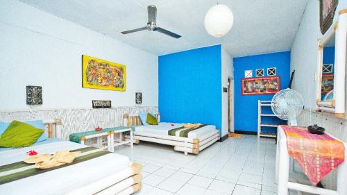 a bedroom with two beds and a blue wall at Rumah Kundun in Gili Trawangan