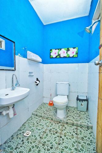 a blue bathroom with a toilet and a sink at Rumah Kundun in Gili Trawangan