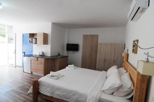 a bedroom with a white bed and a kitchen at Lithos Studios in Voroklini