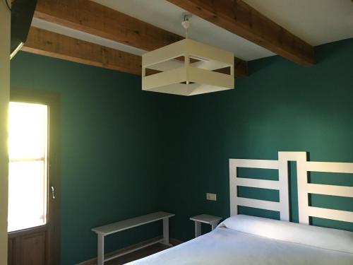 Hotel Rural Casa La Era في Galve: غرفة نوم بجدران خضراء وسرير وثريا