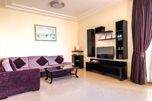 a living room with a purple couch and a tv at Royal Beach Hotel & Resort in Dibba