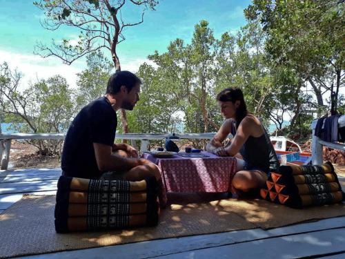 俊島的住宿－岩石景露台旅館，两人坐在阴凉处的桌子上